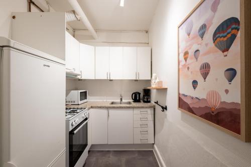 a small kitchen with white cabinets and a refrigerator at Lovely City Apartments in Vibrant Area of Copenhagen in Copenhagen