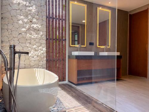 a bathroom with two sinks and a bath tub at Villa Daun Emas in Jimbaran