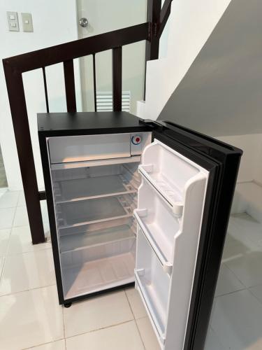 un frigorifero vuoto con la porta aperta accanto a una scala di 2BR Near Clark - Fast Wifi - Self Check-in a Mabalacat