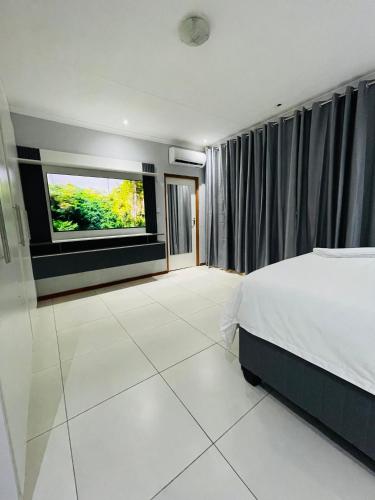 Que Self Catering Apartments - Block7 في غابورون: غرفة نوم مع سرير وتلفزيون بشاشة مسطحة