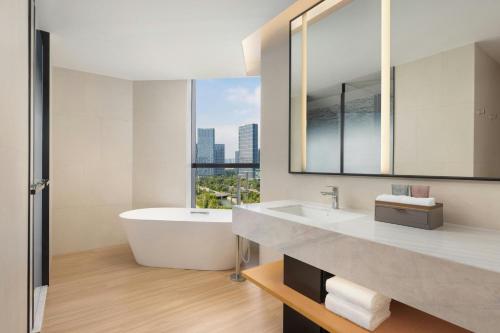 a bathroom with a tub and a sink and a mirror at Fairfield by Marriott Hangzhou Future Sci-tech City in Hangzhou