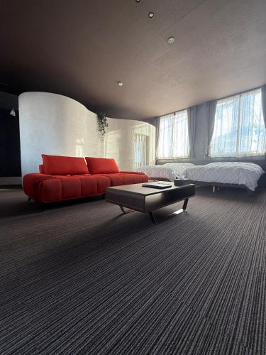 a living room with a red couch and a bed at 欒裏町ouchi uramachi in Matsumoto