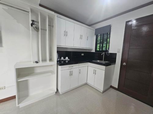 パングラオにあるBliss Suites by SMS Hospitalityの白いキャビネット、シンク、ドア付きのキッチン
