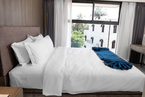 ein Schlafzimmer mit einem weißen Bett und einem großen Fenster in der Unterkunft Lux Inn Hotel in Kinshasa
