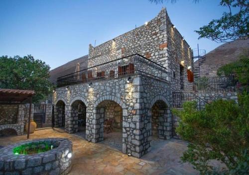 Kitta Mani Towerhouse - Mountain Views & Garden في Koíta: مبنى حجري كبير وامامه نافورة