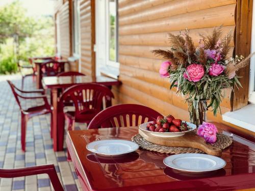 Отель Маленький Рай في زاتوكا: طاولة مع وعاء من الفاكهة والزهور على الشرفة