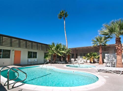 een zwembad met stoelen en palmbomen voor een gebouw bij The Gateway Boutique Vacation Rentals in Desert Hot Springs