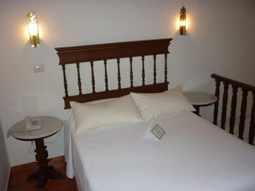 a bed with a wooden headboard and two tables at Meson del Alferez Coatepec in Coatepec