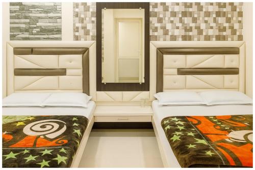 two beds in a room with a mirror at Hotel Premium IN Tulsi GH Near Shri Mahakaleshwar Jyotirlinga Temple - Fully Air Air Conditioning Rooms - Prime Location in Ujjain