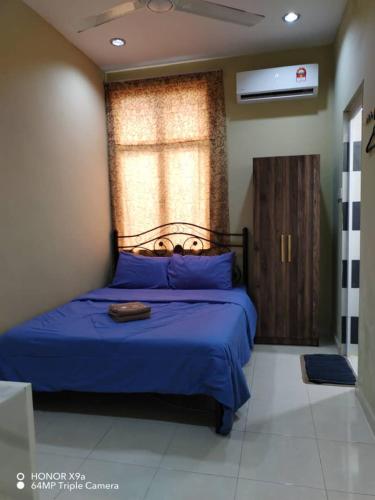 a bedroom with a blue bed with a window at NZ Villa Roomstay in Kangar