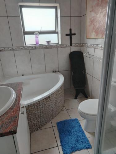 a bathroom with a tub and a toilet and a window at The Treehouse! in Struisbaai