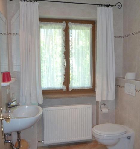 a bathroom with a sink and a toilet and a window at Ferienwohnungen Fontana in Bad Gögging