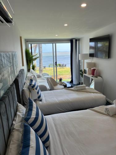 Lakes Resort Toukley في توكلي: صف من الأسرة في غرفة مطلة على المحيط