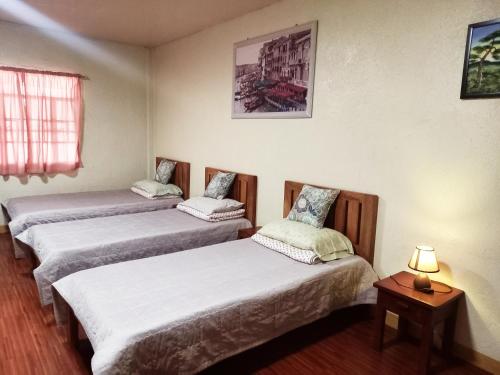 锡朗米妮旅馆的一间设有三张床和一张带台灯的桌子的房间