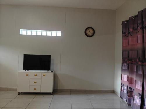 a room with a tv and a clock on a wall at Spring Cottage in Walvis Bay