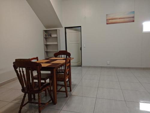 a dining room with a wooden table and chairs at Spring Cottage in Walvis Bay