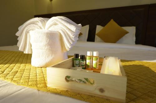 Serenova Resort by ILIF Hotels في مورود: صندوق خشبي يحتوي على مناشف ومستحضرات تجميل موضوع على سرير