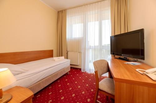 Interferie Chalkozyn w Kołobrzegu في كولوبرزيغ: غرفة فندقية مع سرير وتلفزيون بشاشة مسطحة