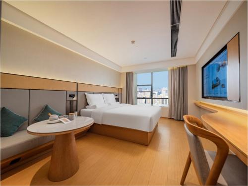 ein Hotelzimmer mit einem Bett, einem Tisch und einem Fernseher in der Unterkunft JI Hotel Chengdu Sichuan Normal University in Chengdu