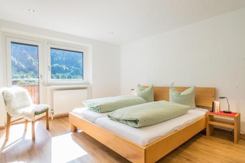 1 dormitorio con 1 cama con silla y ventana en Haus Tramontana, en Gaschurn