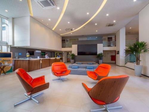 an office lobby with orange chairs and a couch at Novotel Manaus in Manaus