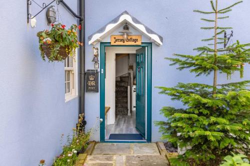 a blue building with a blue door with a sign at Charming Jersey Cottage with parking 8 Guests in Cowes