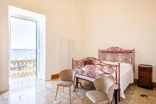 a bedroom with a bed and two chairs and a window at Palazzo Celina in Gallipoli
