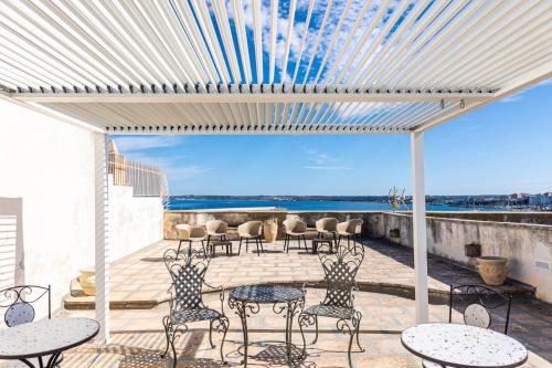 a patio with tables and chairs and a view of the ocean at Palazzo Celina in Gallipoli