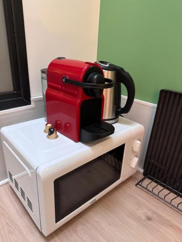 a red coffee maker on top of a microwave at GREEN&PURPLE STUDIO 24-24 Access in Bois-Colombes