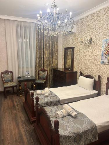 Un dormitorio con dos camas y una lámpara de araña. en Historical Old City Hotel, en Baku