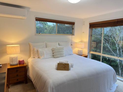 a bedroom with a large white bed with a window at Palacete Beach Resort - entire home in Culburra Beach
