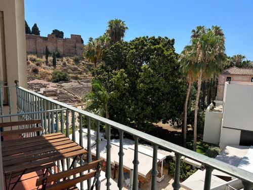 a balcony with two wooden benches and palm trees at Teatro Romano 1 & 2 in Málaga