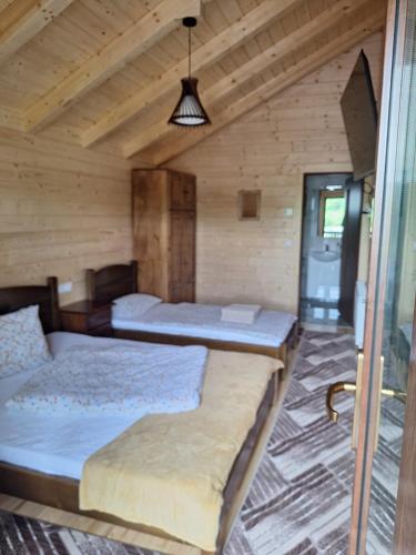 two beds in a room with wooden walls at Baile Figa-Terasa Spa Cazare in Beclean
