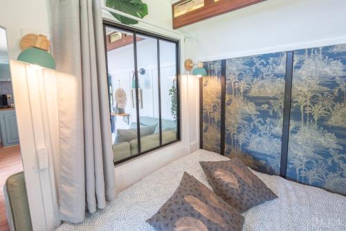 a bedroom with a bed with a large window at Roulotte avec bain nordique privatif chauffé, Séjour calme et bien-être in Fichous-Riumayou