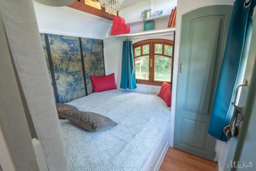 a small bedroom with a bed in a tiny house at Roulotte avec bain nordique privatif chauffé, Séjour calme et bien-être in Fichous-Riumayou