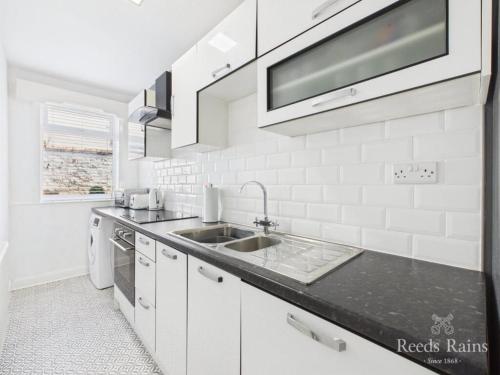 a white kitchen with a sink and a microwave at The Cask Room in Scarborough