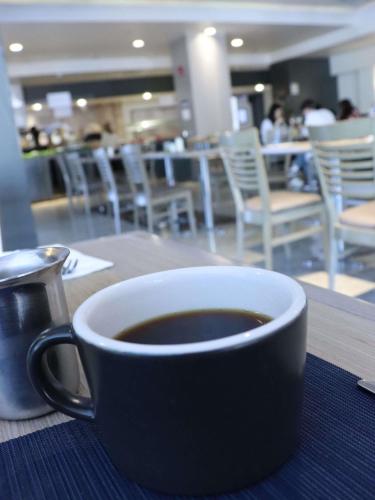 a cup of coffee sitting on top of a table at Novotel Monterrey Valle in Monterrey