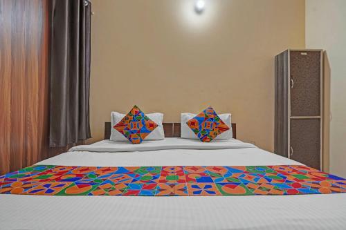 FabHotel Hare Rama في Prayagraj: سرير مع ملاءات ملونة ووسائد عليه