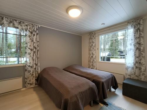 een slaapkamer met twee bedden en een raam bij Syötemaja in Pudasjärvi