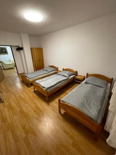drie bedden in een kamer met houten vloeren bij Ubytovanie u Grófa in Turany