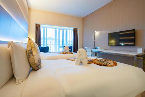 a hotel room with two beds and a flat screen tv at Sanya Phoenix Airport Hotel in Sanya