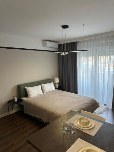 een slaapkamer met een bed en een tafel met glazen erop bij Premium Line Apartman 3 in Sombor