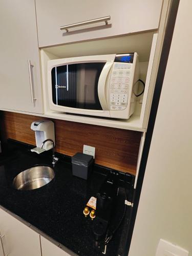 a kitchen with a microwave above a sink at Flat Expo Anhembi WiseSP Accommodations in São Paulo