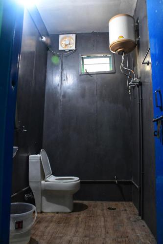 a bathroom with a toilet and a window and a light at Ivan homestay in Kulu