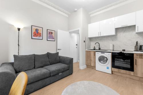 Una sala de estar con un sofá y una cocina. en Modern 2bed Flat 5 min walk to Brixton & Clapham, en Londres