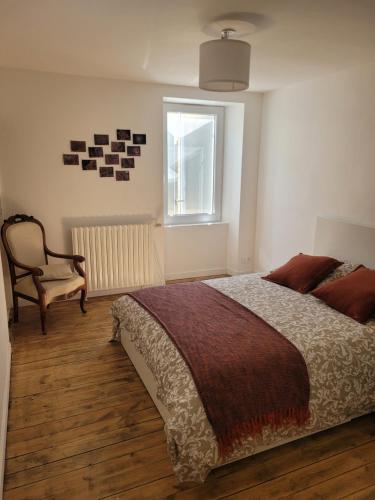 a bedroom with a bed and a chair and a window at la maison du grand mas in Mouret