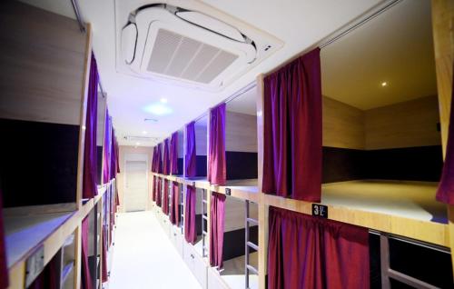 een rij boekenplanken in een kamer met rode gordijnen bij Umaa Sleeping Beds Dormitory in Pārvatīpuram