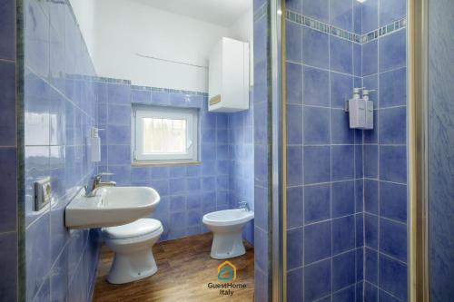 a blue tiled bathroom with a toilet and a sink at Dani's House in Isola Sacra