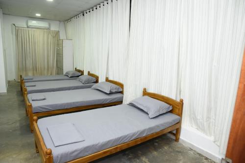 a group of four beds in a room with a window at Colombo Mount Hostel in Mount Lavinia