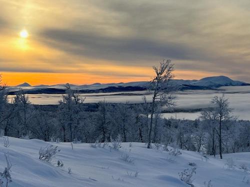 a snowy field with the sun setting in the distance at Mountain Cabin With Great Ski Terrain in Vingelen